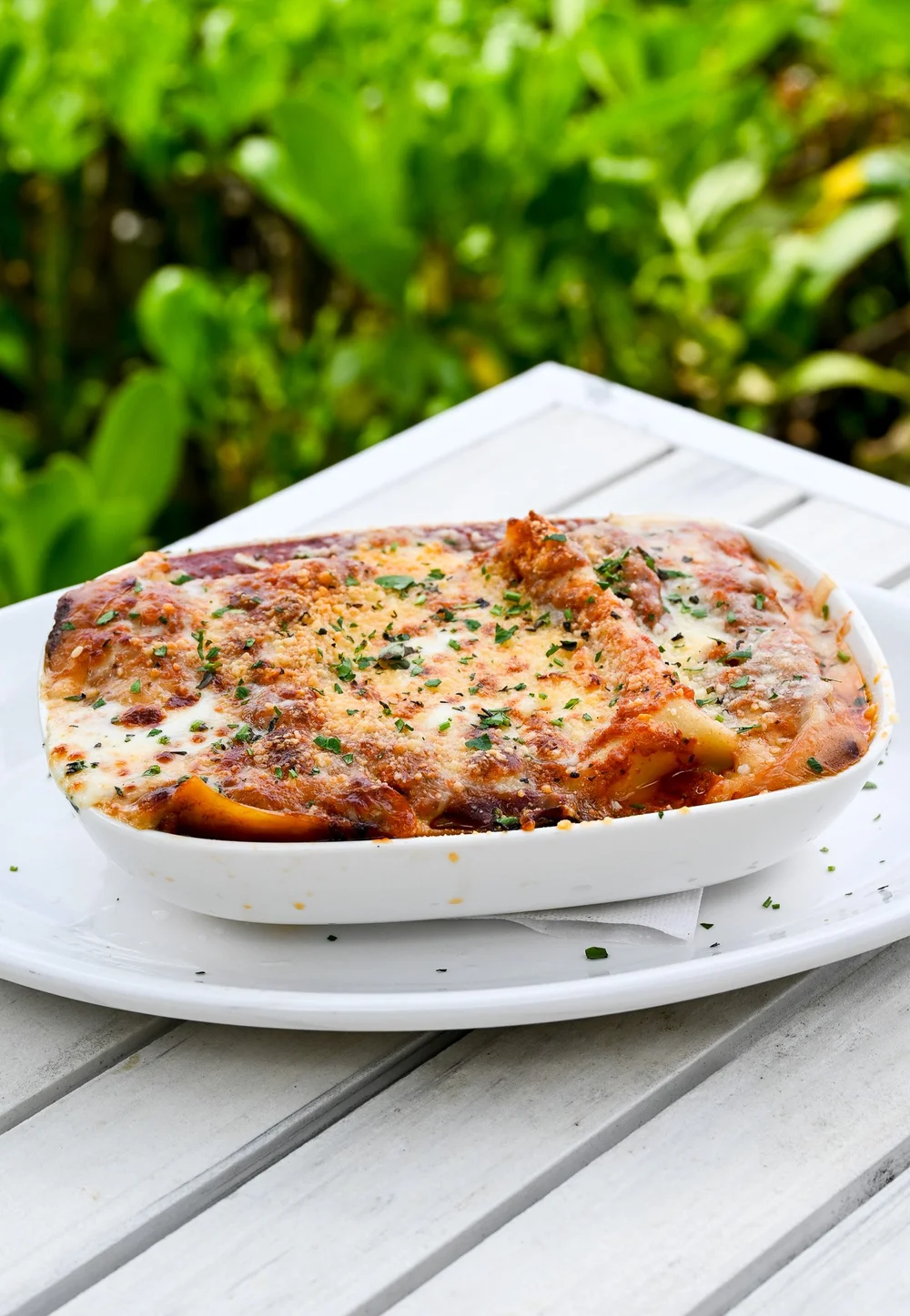 Bubbling baked lasagna in a white dish by the ocean