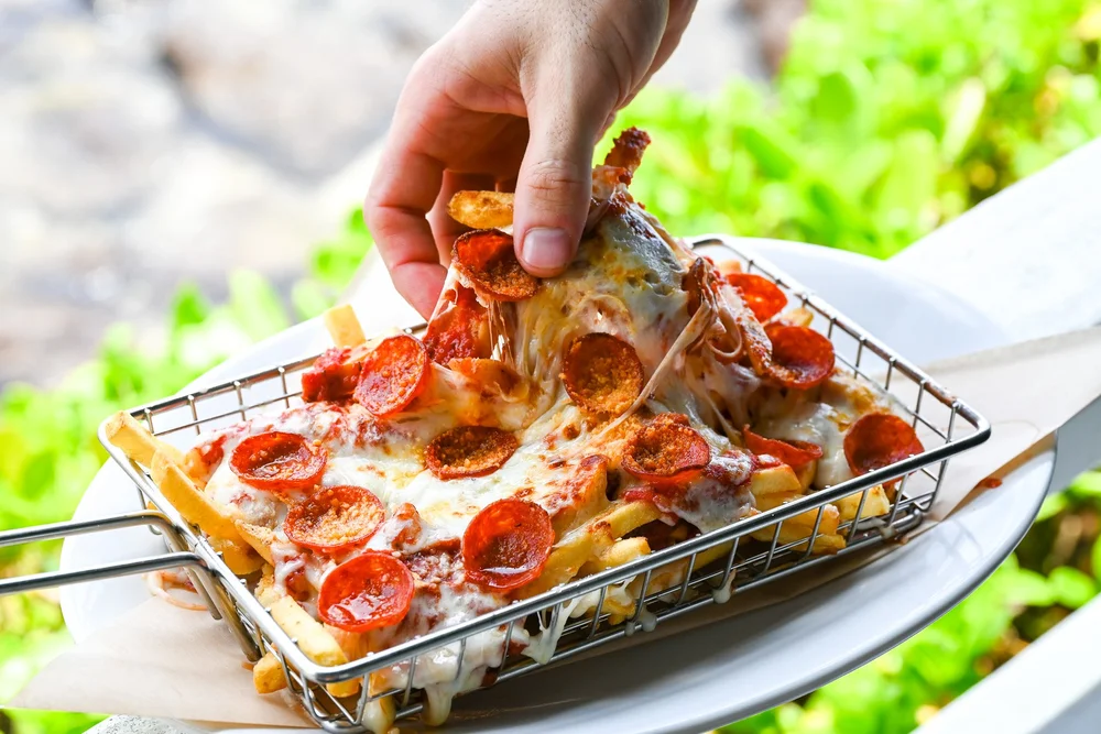 A slice of pepperoni Naples-style pizza being lifted from the pan