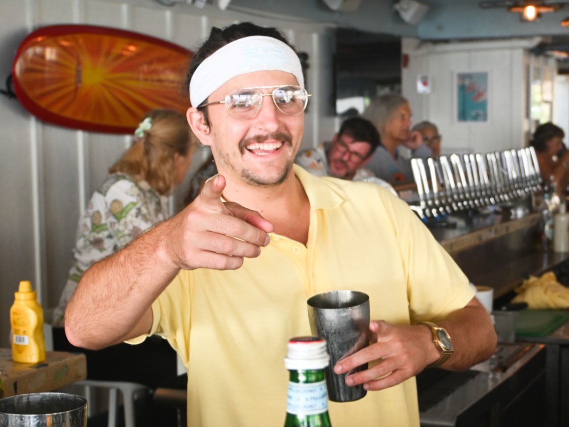 A Kai bartender shaking a cocktail in front of the tap wall