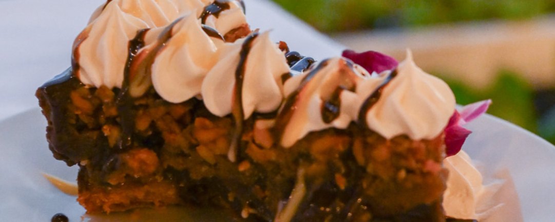 Chocolate macadamia nut pie with whipped cream by the water at dusk